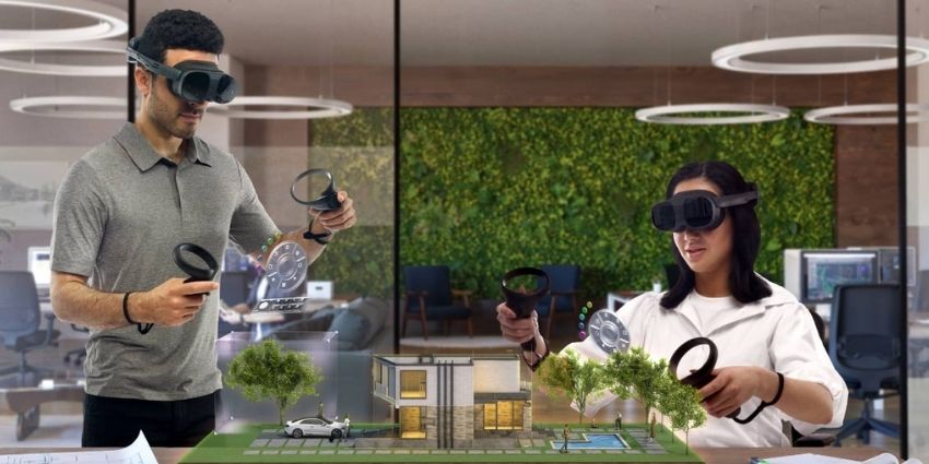 Two people by a table collaborating on a project wearing a HTC Vive headset